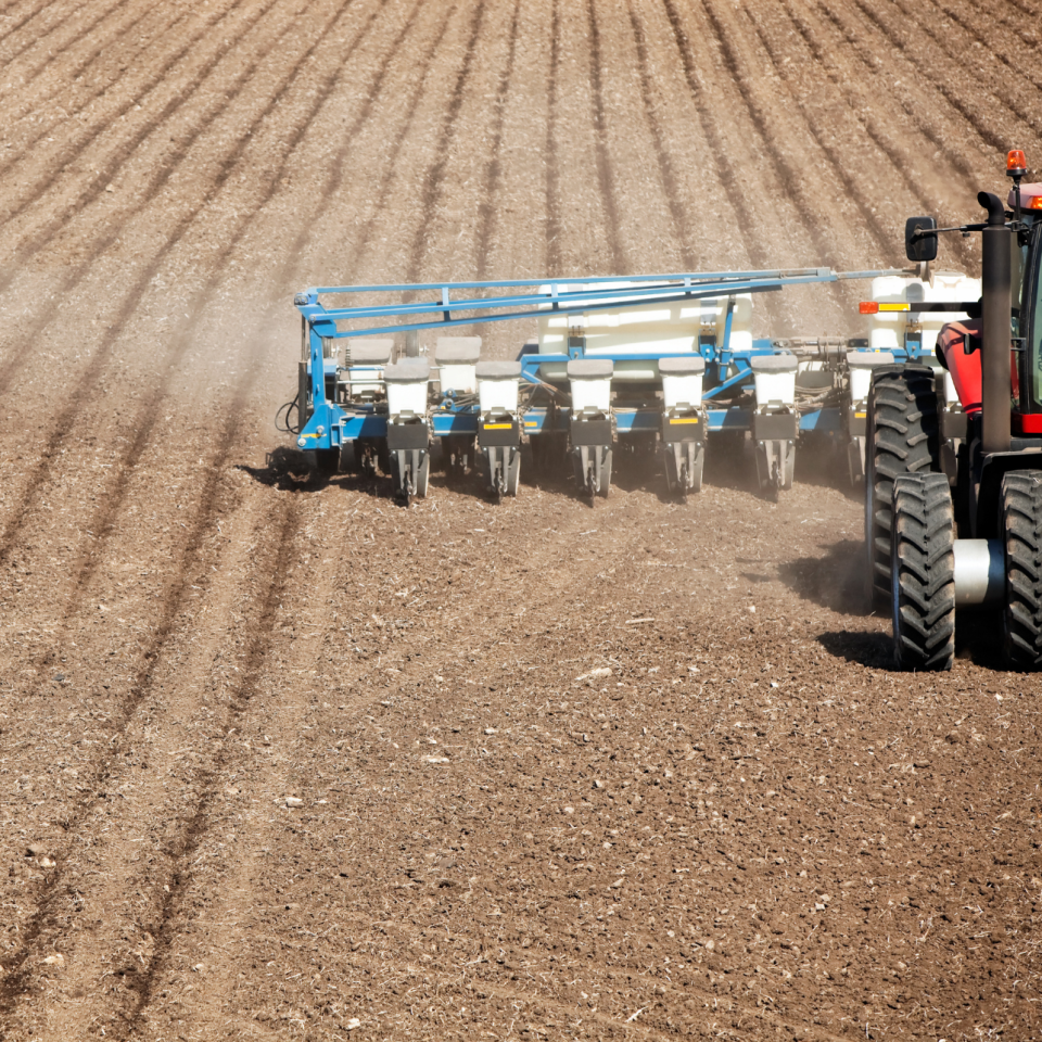 Close up of farm machinery doing spring seed planting in field.